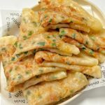 Stack of crispy scallion pancakes served on a plate.