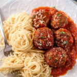 Spaghetti served with meatballs in marinara sauce and grated cheese.