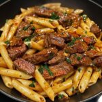 Penne pasta mixed with juicy beef strips in a savory sauce.