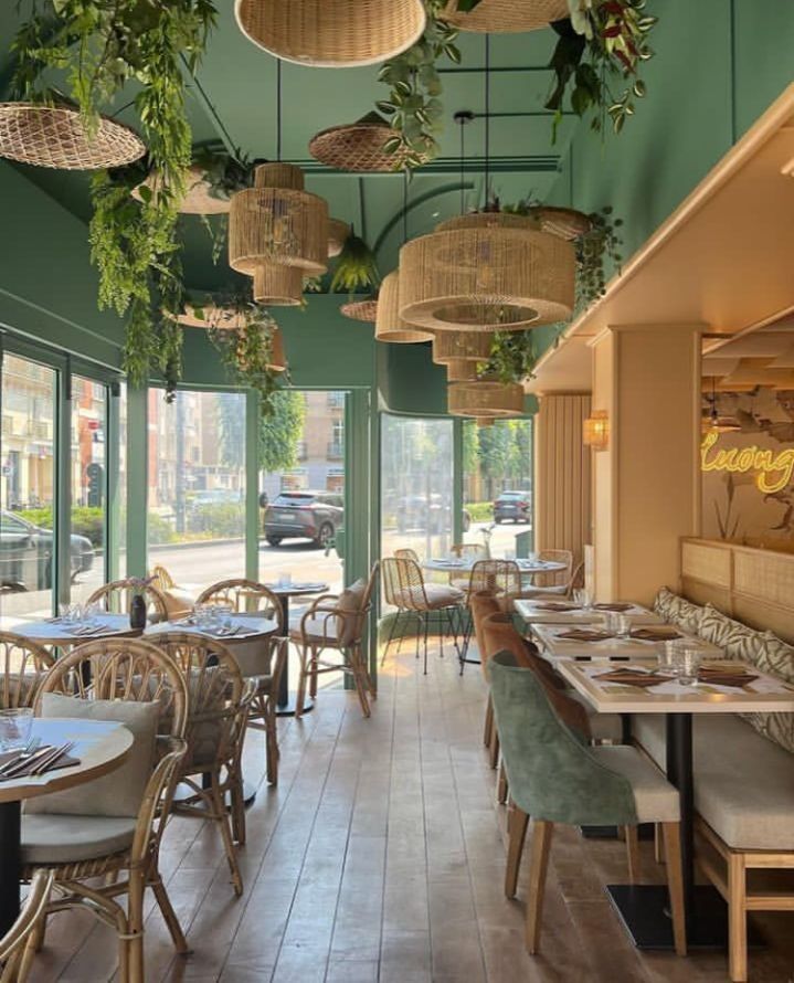 “Bright and cozy restaurant seating area with greenery and elegant wooden furniture in Bangalore”