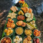 “Traditional Indian sweets and snacks arranged beautifully on banana leaves for a festive offering.”