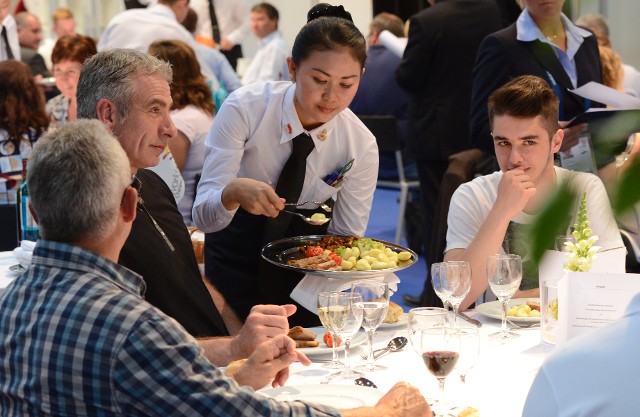 A server serving food to guests at a busy restaurant table.