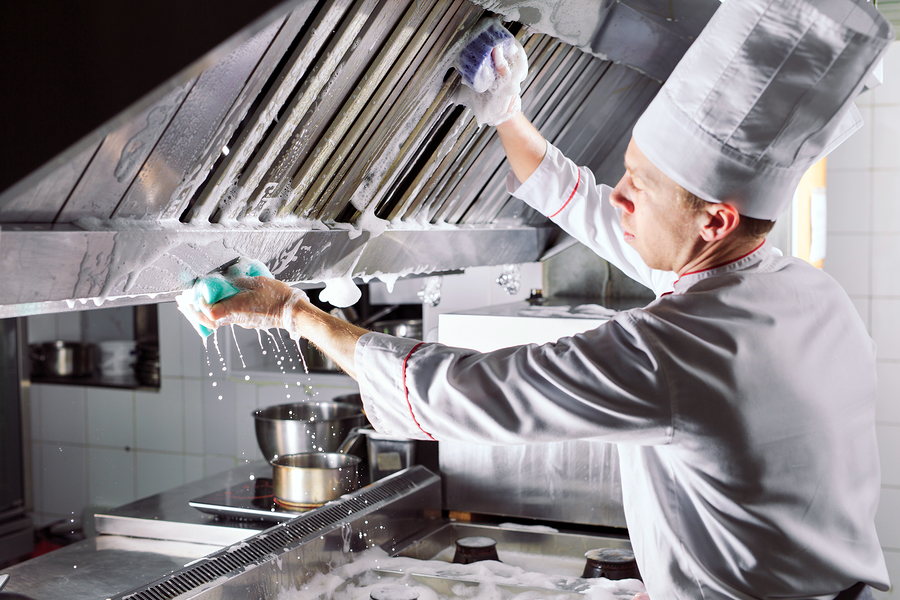 Chefs performing deep cleaning on stainless steel kitchen counters to maintain daily hygiene standards.