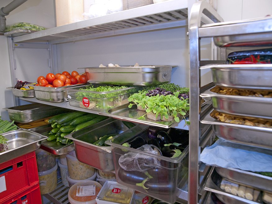 Organized restaurant cold storage with labeled containers and temperature-controlled shelves to maintain ingredient freshness